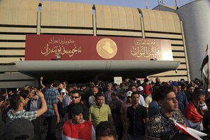 Supporters of Shiite cleric Muqtada al-Sadr gather outside parliament in Baghdad's Green Zone, Saturday, April 30, 2016. Dozens of protesters climbed over the blast walls and could be seen storming the Parliament building, carrying Iraqi flags and chanting against the government.