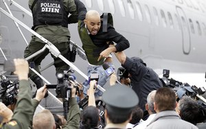 Alleged Peruvian drug trafficker Gerson Galvez shouts at the press as he is escorted by police officers into a Peruvian Air Force plane, in Bogota, Colombia, Sunday, May 1, 2016.