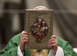 Pope Francis holds the Gospel book as he celebrates the opening Mass of the Synod of bishops, in St. Peter's Basilica at the Vatican, Sunday, Oct. 4, 2015.