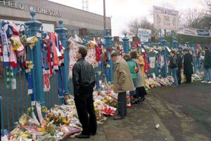 In this file photo dated April 17, 1989, soccer fans arrive to pay their respects and look at the flowers, scarves and banners, left on the gates at Hillsborough Football Stadium, after the Hillsborough April 15 tragedy when fans surged forward during the Cup semi-final between Liverpool and Nottingham Forest at Hillsborough Stadium killing 96 people.