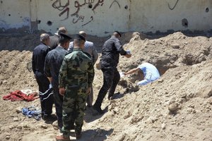 File - Iraqi security forces including a forensics team work at the site of a mass grave, one of two discovered containing the bodies of dozens of men, women and children killed by Islamic State group militants, in the stadium area in Ramadi, 115 kilometers (70 miles) west of Baghdad, Iraq, Tuesday, April 19, 2016.