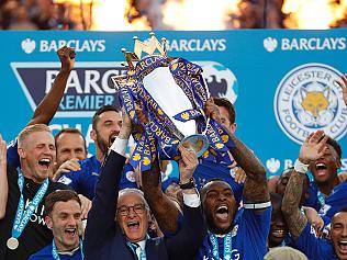 Leicester City's Italian manager Claudio Ranieri (C) and Leicester City's English defender Wes Morgan hold up the Premier league trophy after winning the league and the English Premier League football match between Leicester City and Everton at King Power Stadium in Leicester, central England on May 7, 2016. / AFP PHOTO / ADRIAN DENNIS / RESTRICTED TO EDITORIAL USE. No use with unauthorized audio, video, data, fixture lists, club/league logos or 'live' services. Online in-match use limited to 75 images, no video emulation. No use in betting, games or single club/league/player publications. /