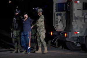 Mexican drug lord Joaquin "El Chapo" Guzman is escorted by soldiers and marines to a waiting helicopter, at a federal hangar in Mexico City, Friday, Jan. 8, 2016.