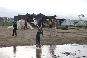 Refugee children play in a puddle at the northern Greek border point of Idomeni, Greece, Saturday, May 7, 2016.