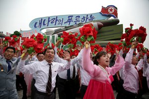 North Korean parade participants wave decorative bouquets of flowers and carry their country's national flag as they march with different types of models of missiles at the Kim Il Sung Square on Tuesday, May 10, 2016, in Pyongyang, North Korea. Hundreds of thousands of North Koreans celebrated the country's newly completed ruling-party congress with a massive civilian parade featuring floats bearing patriotic slogans and marchers with flags and pompoms. (AP Photo/Wong Maye-E)