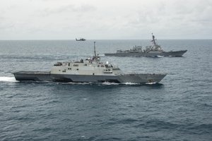 The littoral combat ship USS Fort Worth, bottom, the guided missile destroyer USS Sampson, and an MH-60R Seahawk from Helicopter Maritime Strike Squadron (HSM) 35 operate together in the Java Sea while supporting the Indonesian-led search effort for AirAsia flight QZ8501, 14 January, 2015.