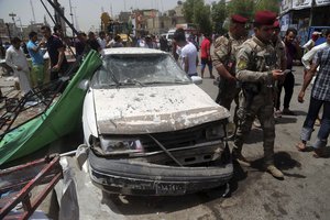 Security forces and citizens inspect the scene after a car bomb explosion at a crowded outdoor market in the Iraqi capital's eastern district of Sadr City, Iraq, Wednesday, May 11, 2016.