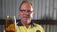 Man holds wine glass with thickened, dark wine inside