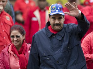 FILE - In this May 1, 2016 file photo, Venezuela's President Nicolas Maduro waves to supporters alongside first lady Cilia Flores during a labor day march in Caracas, Venezuela. Maduro frequently accuses the U.S. of working with the opposition to sow dissent where none exists.