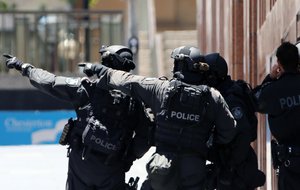 In this Dec. 15, 2014 file photo, armed police officers point as they stand at the ready close to a cafe under siege at Martin Place in Sydney, Australia.