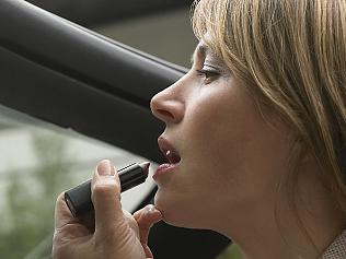 Woman Sitting Applying Make-up in a Vehicle Mirror. Putting on lipstick in a car or while driving