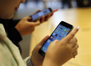 Customers try out a new Apple iPhone 6S at an Apple store on Chicago's Magnificent Mile, Friday, Sept. 25, 2015, in Chicago.