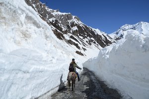 A Kashmiri man on a horse rides past walls of snow on the Zojila Pass, about 110 kilometers (68 miles) north of Srinagar, Indian controlled Kashmir, Saturday, April 30, 2016.