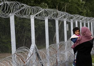 A woman holds her child in the makeshift refugee camp near the Horgos border crossing into Hungary, near Horgos, Serbia, Wednesday, May 18, 2016.