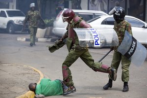 FILE - In this Monday, May 16, 2016 file photo, a Kenyan riot policeman repeatedly kicks a protester as he lies in the street after falling down while trying to flee from them, during a protest in downtown Nairobi, Kenya.