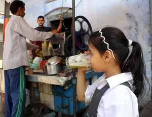 An Indian school girl drinking sugar cane juice during scorching heat in Jammu, Jammu and Kashmir State, India, 25th April 2016.