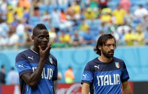 Italy's Mario Balotelli, left, and Andrea Pirlo warm up prior to the group D World Cup soccer match between Italy and Uruguay at the Arena das Dunas in Natal, Brazil, Tuesday, June 24, 2014.