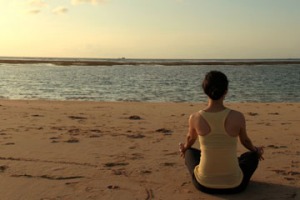 Young fit woman doing yoga by the beach.