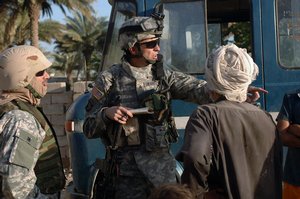  US Army (USA) Sergeant (SGT) Swainston (center), Delta Company (D Co), 4th Platoon (PLT), 1st Battalion (BN), 502nd Infantry Regiment (1/502nd), 101st Airborne Division (Air Assault), speaks with a local Iraqi man while on patrol in Mahmudiyah, Babil Pro