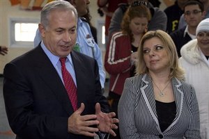 Likud Party leader Benjamin Netanyahu speaks to journalists as his wife Sara listens after voting in Israel's general election at a polling station in Jerusalem, Tuesday Feb. 10, 2009. Israeli officials said Tuesday that polls had opened for the general election that pits former Prime Minister Benjamin Netanyahu and his Likud Party against Foreign Minister Tzipi Livni and her ruling Kadima