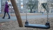 Eine Schaukel auf einem Spielplatz in Hamburg-Harburg - im Hintergrund geht ein Kind vorbei. (picture alliance / dpa / Malte Christians)