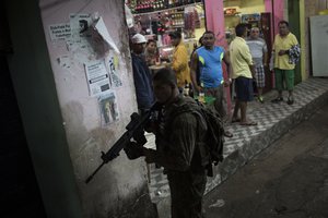 A police officer aims his weapon during a police operation at Rocinha slum in Rio de Janeiro, Brazil, Friday, May 20, 2016.