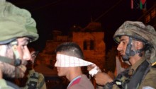 Soldado esposando y vendando los ojos a un joven palestino