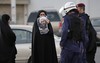 A Bahraini protester holds up a picture of Saudi Shiite cleric Sheikh Nimr al-Nimr toward riot police officers in Daih, Bahrain, a largely Shiite suburb of the capital, Monday, Jan. 4, 2016.