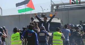 Young Palestinian man sits defiantely on army jeep