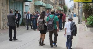 The delegation on Shuhada Street, with Shuada checkpoint in the background and a group of settlers passing them