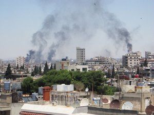 File - Smoke billows skyward as homes and buildings are shelled in the city of Homs, Syria, 9 June, 2012.