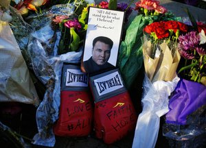 Boxing gloves and a message sit amongst flowers  at a makeshift memorial to Muhammad Ali at the Muhammad Ali Center, Saturday, June 4, 2016, in Louisville, Ky. Muhammad Ali died Friday at age 74.