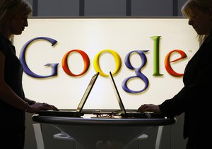 In this April 17, 2007 file photo, exhibitors work on laptop computers in front of an illuminated sign of the Google logo at the industrial fair Hannover Messe in Hanover, Germany.