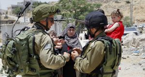 Israeli soldiers stop Palestinians at the entrance of Yatta near the West Bank city of Hebron June 9, 2016. The Israeli army entered the village in search for clues leading to an attack the previous night in the Israeli city of Tel Aviv in which four people were killed and 16 others wounded. The two Palestinians assailants who carried out the attack came from Yatta, according to Israeli authorities. Israel said it had suspended entry permits for 83,000 Palestinians during the holy Muslim month of Ramadan following the shooting attack. Photo by Wisam Hashlamoun