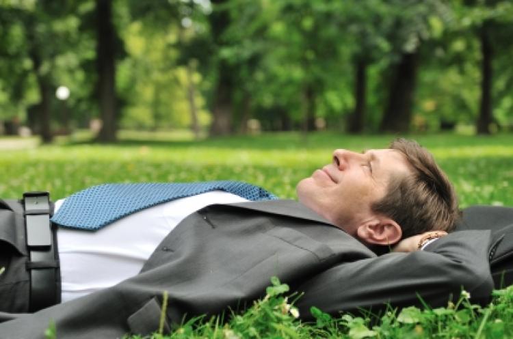 mature business man lying on grass and relaxing in park