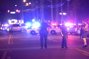 Police officers stand guard down the street from the scene of a shooting involving multiple fatalities at a nightclub in Orlando, Fla., Sunday, June 12, 2016.