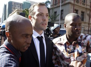 File - Oscar Pistorius, center, escorted by unidentified man as he leaves the high court in Pretoria, South Africa, Monday, April 18, 2016.