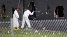 FBI agents standing outside the Pulse nightclub look into a large hole in the rear wall of the club.