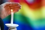 A candle burns in front of a pride flag while community members gather for a vigil  to honor the victims of the attack ...