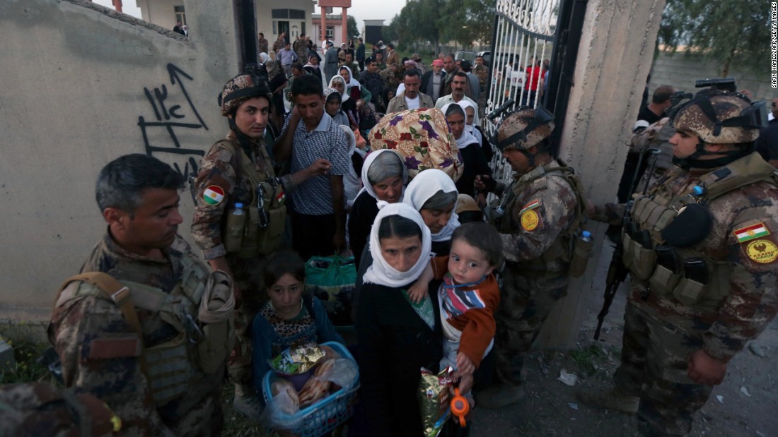 Kurdish Peshmerga forces help Yazidis as they arrive at a medical center in Altun Kupri, Iraq, on April 8.