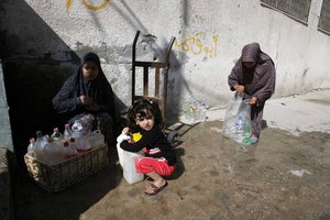 File - Palestinians fill water from pipes provided by the United Nations Relief and Works Agency (UNRWA) headquarters in the Rafah refugee camp in the Southern Gaza Strip on April 6, 2014.