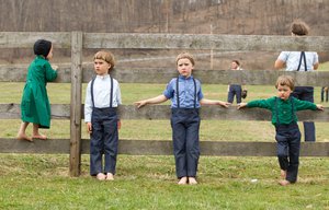 Amish children relax by a fence during a baseball game in Bergholz, Ohio on April 9, 2013. (AP Photo/Scott R. Galvin)