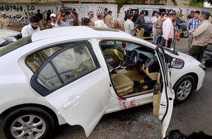 Pakistani investigators and media persons gather next to blood-stain car of famous Sufi singer Amjad Sabri at the site of firing incident in Karachi, Pakistan, Wednesday, June 22, 2016. Pakistani police say gunmen have killed a famous Sufi singer in the southern port city of Karachi. Police officer Arif Mahar says Sabri was shot several times Wednesday while driving in his car. Sabri's brother, who was also in the car, was wounded. (AP Photo/Shakil Adil)