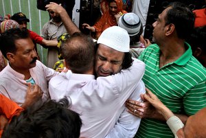 People comfort to the brother, center, of famous Sufi singer Amjad Sabri, who was killed by unknown attackers, at outside his residence in Karachi, Pakistan, Wednesday, June 22, 2016.