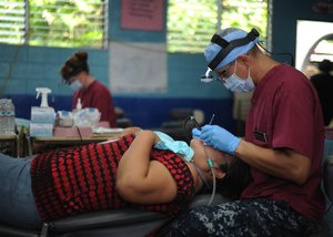 Hospital Corpsman 1st Class Darwin Flores, from San Salvador, El Salvador, performs a dental cleaning during a Continuing Promise 2011 community service medical project.