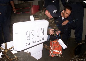 File - U.S. Navy Lt. j.g. Jason S. Hall (right) watches as FBI Agent Duback (left) tags the cockpit voice recorder from EgyptAir Flight 990 on the deck of the USS Grapple (ARS 53) at the crash site, 13 November, 1999.