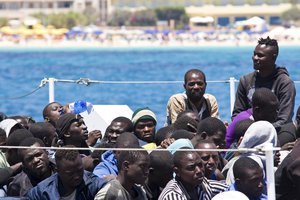 Migrants wait to disembark from a Coast Guard ship that rescued them at sea, in the Island of Lampedusa, Italy, Tuesday, June 23, 2015.