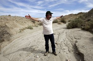 Doug Given, a seismologist and project leader from the U.S. Geological Survey, stands in a dry creek bed and uses his arms to indicate the approximate direction taken by a fault zone of the San Andreas Fault, as scientists from the USGS install an earthquake monitoring station near the fault nearby, in a desert canyon near Thermal, Calif.