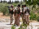 Fighters from the Syria Democratic Forces (SDF) stand with their weapons in an orchard near Manbij, in Aleppo Governorate, Syria.