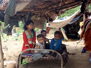 File - Poor Indian children sitting outside their tent home on a folding bed in Jammu, India, 24 May 2016. Extreme poverty is common among members of scheduled castes and tribes in the country's rural areas.